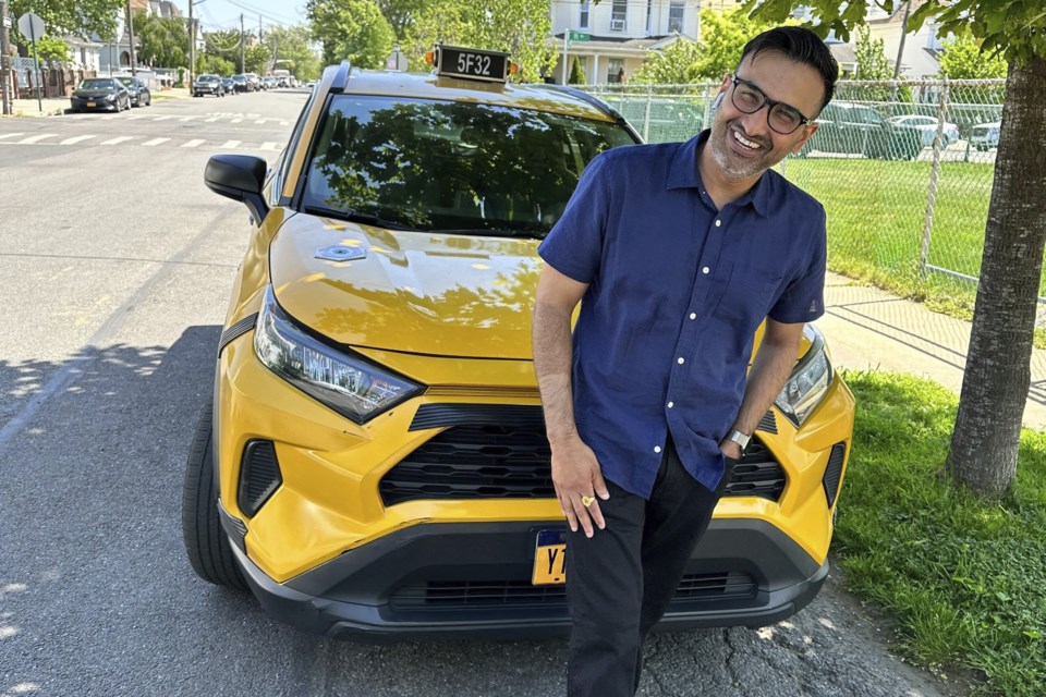 New York City cab driver Sukhcharn Singh poses for a photo with his taxi in the Queens borough of New York, Wednesday, May 17, 2023. Prince Harry and his wife, Meghan, were pursued in their car by photographers after a charity